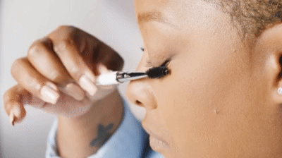 woman demonstrating how to brush lash extensions
